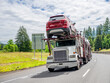© vit - Capacious car hauler big rig semi truck transporting cargo on modular semi trailer driving on the summer highway road
