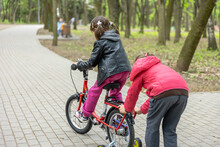 Children Ride A Bike For A Walk In The Park.