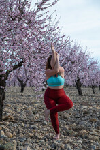 Plus Size Woman Doing Yoga In Eagle Pose In Blooming Garden