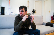 Serious blind man using smartphone on sofa