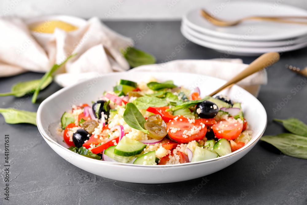 Bowl with couscous and vegetables on dark background, closeup