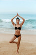 © verona_studio - Beautiful young woman meditation in a yoga pose at the beach. Girl practices yoga. Fitness female