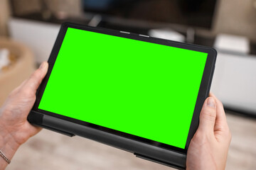 close-up of a tablet with a green screen in female hands. template for advertising, or montage.