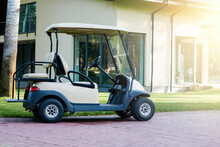 Outdoor Recreation. A White Golf Cart Is Parked Near The Modern Cottage House. Electric Car In The Parking Lot Of The Resort Area