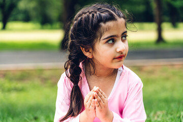 Portrait of happy little muslim girls child with hijab dress smiling and looking at camera in the park