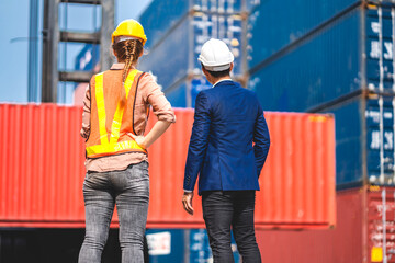 Professional of two engineer container cargo foreman in helmets working standing and using walkie talkie checking stock into container for loading.logistic and business export