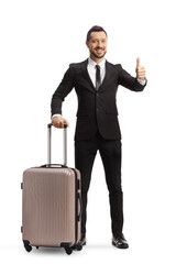 Wall Mural - Full length portrait of a businessman with a suitcase on wheels showing thumbs up