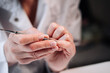 © marozzau - Home manicure. In the photo, a woman in a white coat is using a cuticle lifting tool.