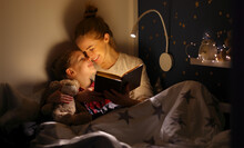 Cheerful Mother And Son Cuddling And Reading Book