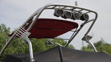 Close Up Tower Targa Top, A Pole For Towing Water-skiing On A Motor Boat With Speakers And A Holder Mount For Wake Riding At Summer Day Against Green Trees Background, Watersports Activity