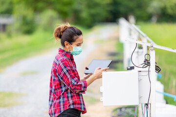 A young woman is checking the system of the watering control panel in the agricultural garden.