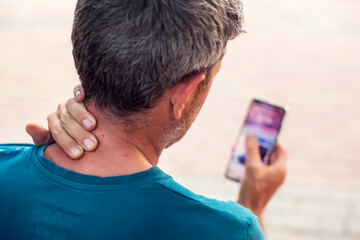 Neck pain using smartphone outdoor. Healthcare, lifestyle and technology concept