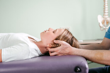 Massage therapist performing cranial sacral therapy on a female child patient and using a gentle touch to manipulate the joints in the cranium or skull