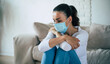 © My Ocean studio - Young woman in deep depression is sitting on the couch in safety medical mask during coronavirus quarantine