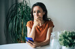 © My Ocean studio - Sad, frustrated young brunette woman is crying with smartphone in hands while she sitting on the chair at apartment