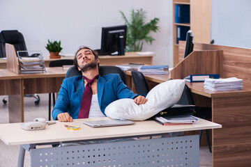 Young male employee coming to work straight from bed