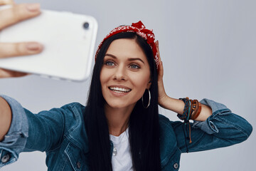 Wall Mural - Beautiful young woman in bandana making selfie and smiling