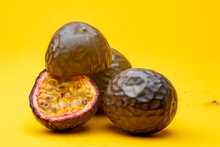 Grouping Of Maracuja Or Brazilian Tropical Passion Fruit Studio Still Life Against A Yellow Background With One Cut Open Showing The Inside Pulp Flesh
