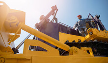 Industrial Portrait Of Working Man, Excavator Driver Climbs Into Cab To Perform Work On Construction Site