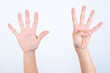 © Jihan - hands with pink manicure over white background pointing up with fingers number nine.