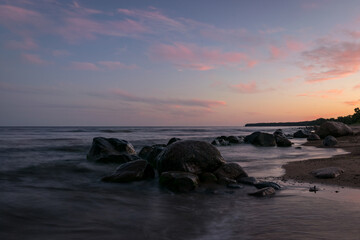 Wall Mural - rocky sea shore before sunrise, dark stone silhouettes and colorful sky