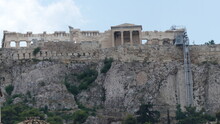 Ground View Of Greek Parthenon With Stone Wall And Castle Ruins With Light Blue Sky Above
