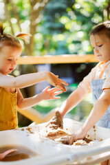 happy children play with sand and water in sensory baskets on the outdoor sensory table, sensory ear