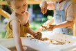 Happy children play with sand and water in sensory baskets on the outdoor sensory table, sensory early development, montessori. Baby hands with sand and water close up, soft focus
