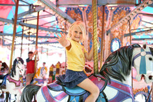 Happy Little Child On Merry Go Round Horse At Carnival