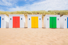 Bright, colurful beach huts lined up in a row on a hot sunny summer day at the seaside holiday beach resort  Woolacombe Bay, North Devon, England.