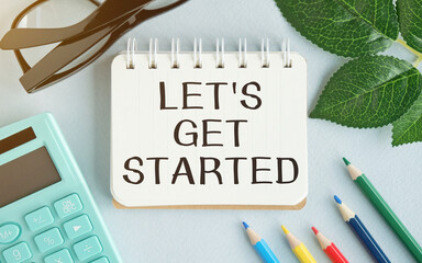 Wall Mural - LET'S GET STARTED text concept write on notebook with office tools on blue background