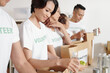 © DragonImages - Group of young volunteers packing groceries in paper packages when working in shipping delivery charitable organization
