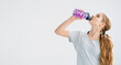 © golubovy - Fitness hydration. Sport banner. Fresh start. Kids healthy lifestyle. Thirsty athletic girl drinking mineral water from bottle isolated on light copy space background.