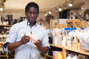 Wall Mural - Portrait of adult African American choosing dispenser for oil and condiments in kitchen utensils department of home furnishings store