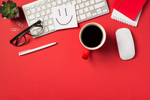 Top View Photo Of Sticker Note Paper With Drawn Smiling Face On White Keyboard Mouse Plant Glasses Clips Pen Red Cup Of Coffee And Two Copybooks On Isolated Vivid Red Background With Copyspace