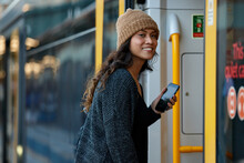 Asian Woman Getting On Train With Mobile Phone