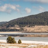 Fototapeta Łazienka - Natural landscape. White snow on the coast and blurry reflections on the frozen water surface of Batak Dam, lake in the Rhodope Mountains, Bulgaria.