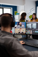 Wall Mural - Videographer employee having video conference wearing headset editing client movie, getting feedback on commercial project. Freelancer using post production software on pc in creative office.