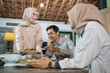 © Odua Images - a girl in a hijab prepares and brings a plate of fried chicken to eat together in the dining room of a traditional house