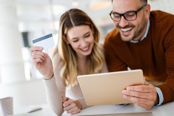 Cheerful young couple doing online shopping with tablet