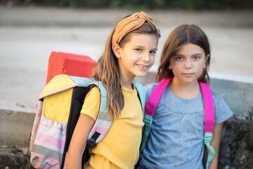 Wall Mural - Two little school girls outside. Looking at camera.