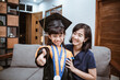 © Odua Images - Kindergarten graduation. Happy asian family graduate at home. elementary school student at home celebrating