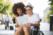 © auremar - two friends visiting foreign city one sitting in wheelchair