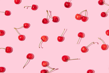 Creative pattern made with bright red cherries  on pastel pink background.  Summer fruit idea. Trendy summer fruit concept. 80s, 90s retro aesthetic Minimal flat lay.