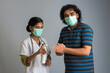 Portrait of young woman doctor and young man using or showing a sanitizing gel from a bottle for hands cleaning.