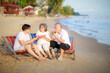 © sutthichai - Happy Asian family enjoy talking together on the sunbed on the beach side restaurant.
