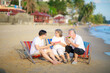 © sutthichai - Happy Asian family enjoy talking together on the sunbed on the beach side restaurant.