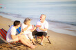 © sutthichai - Happy Asian family enjoy talking together on the sunbed on the beach side restaurant.