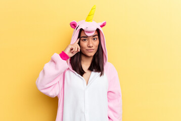 Wall Mural - Young mixed race woman wearing a unicorn pajama isolated on yellow background pointing temple with finger, thinking, focused on a task.