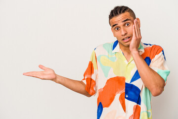 Young venezuelan man isolated on white background impressed holding copy space on palm.